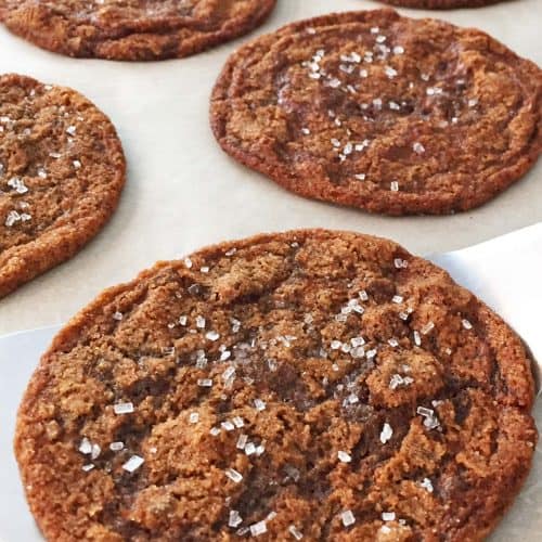 Five ginger bacon grease cookies on a parchment lined baking sheet