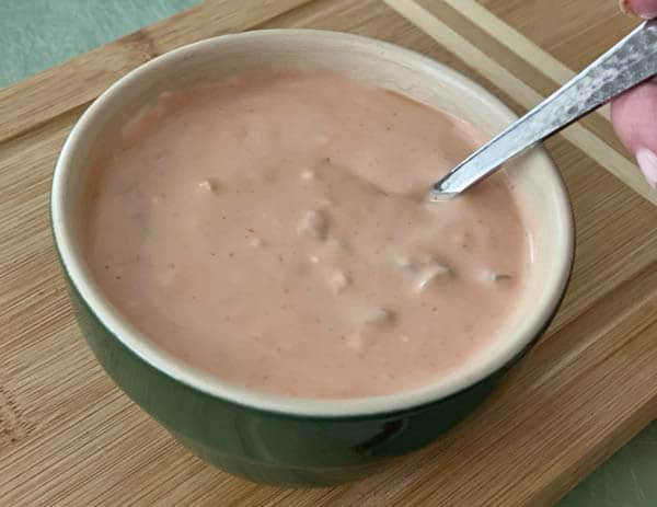 Thousand island dressing in a green bowl with a silver spoon.