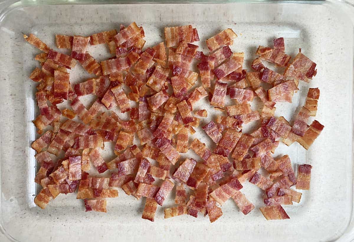 One pound of cooked, chopped bacon in a clear glass 9 by 13 inch baking dish