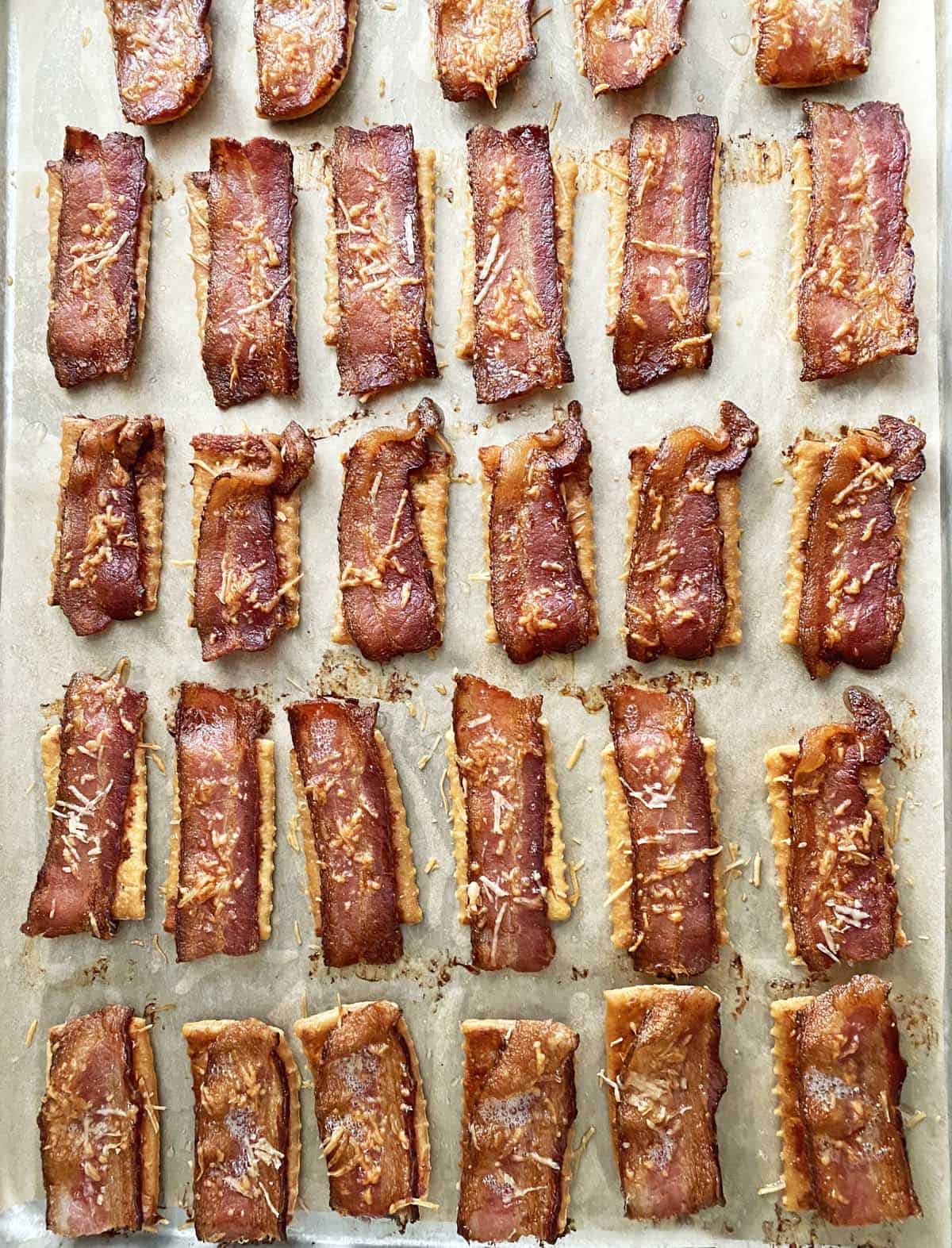 Cooked bacon crackers on a parchment paper lined baking sheet