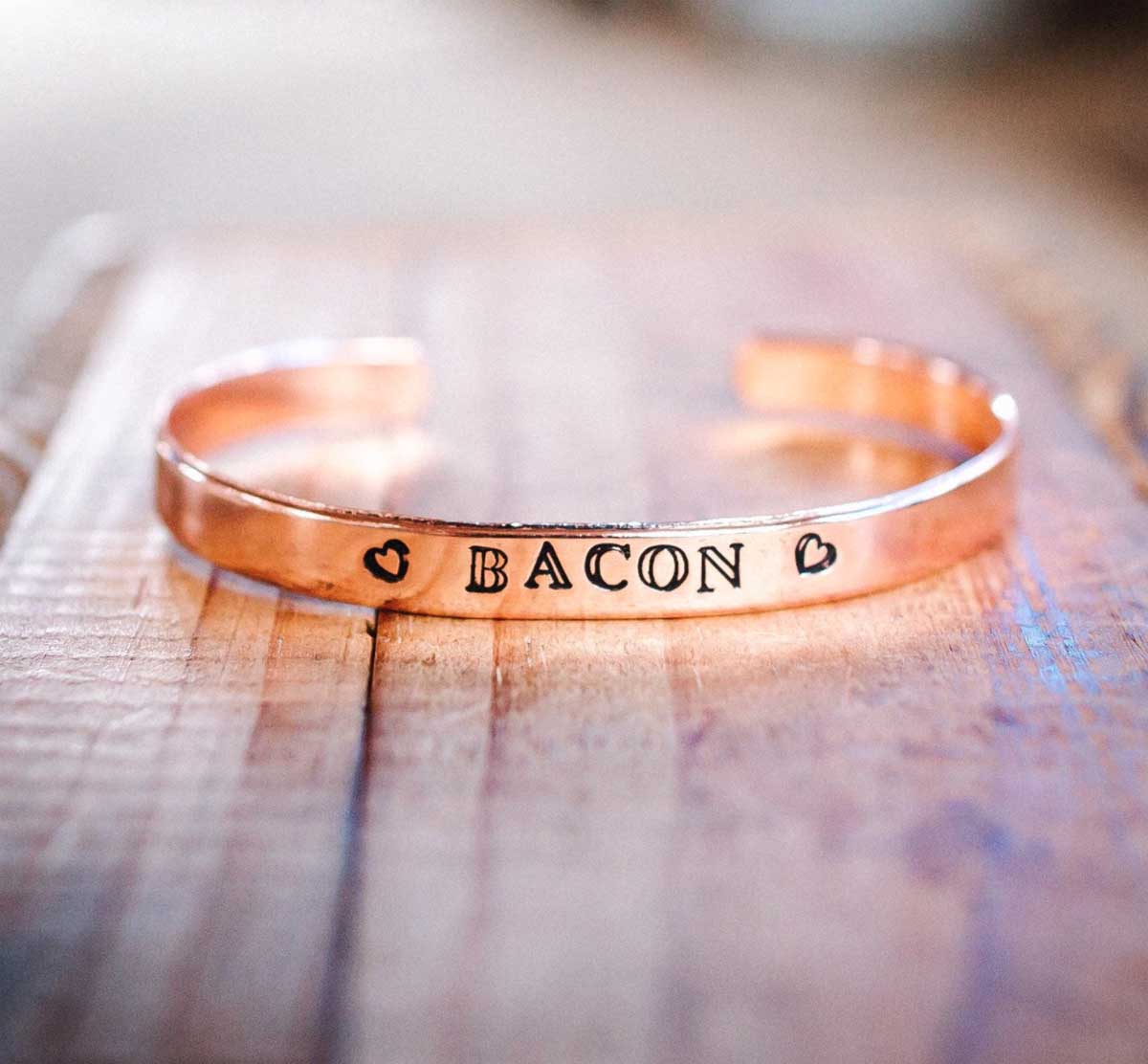 A copper bracelet with the word "BACON" hand stamped across the front.