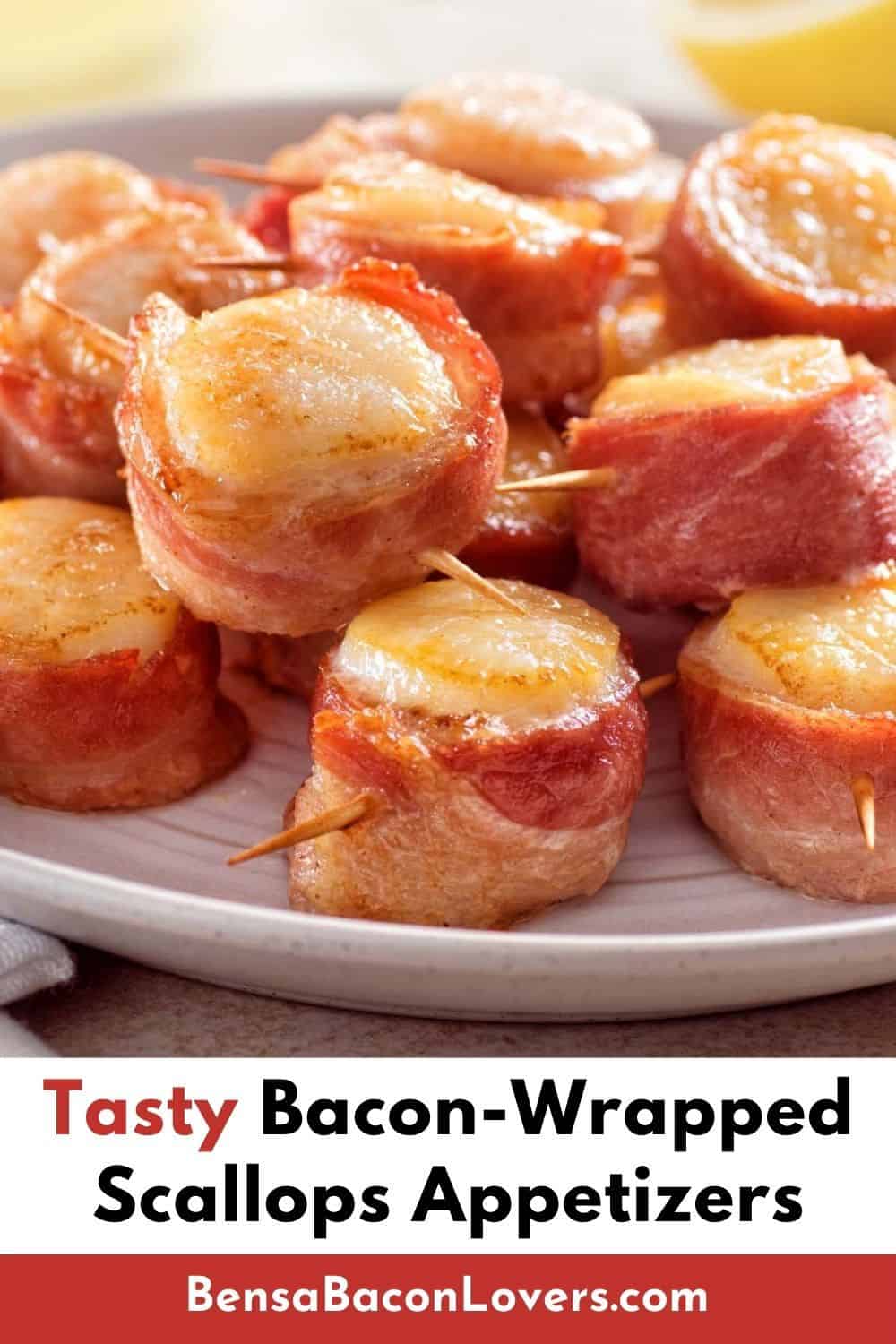 Tasty cooked bacon wrapped scallops on a platter with a fresh lemon half in the background.