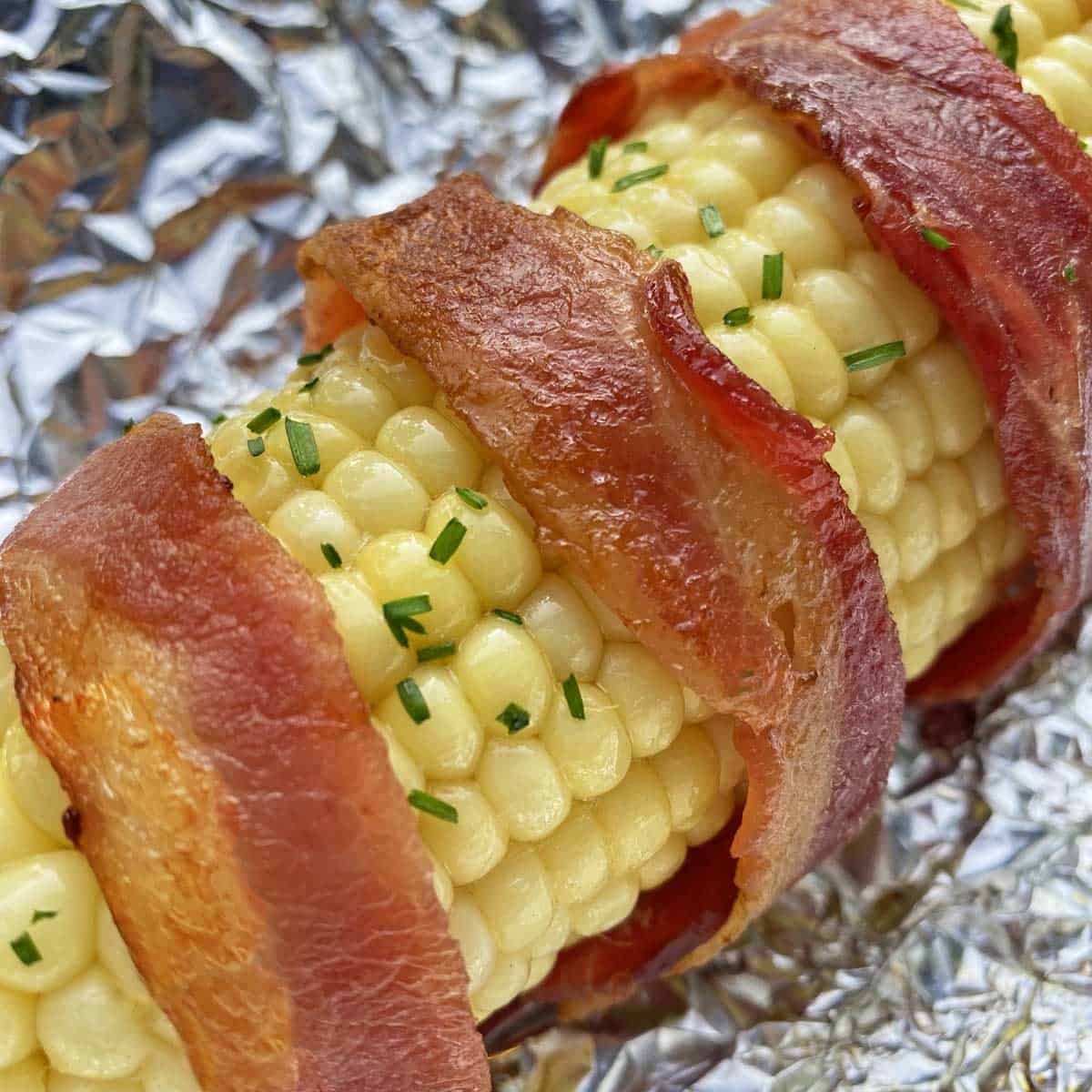 Close up of bacon wrapped corn on foil