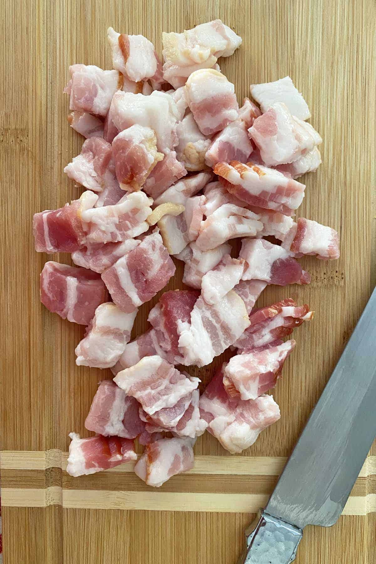a knife and chopped bacon on a cutting board.
