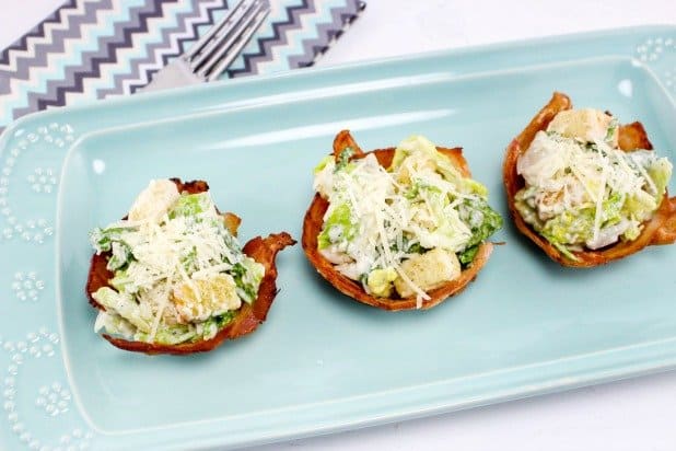 3 caesar salad bacon cup appetizers on a pale blue platter
