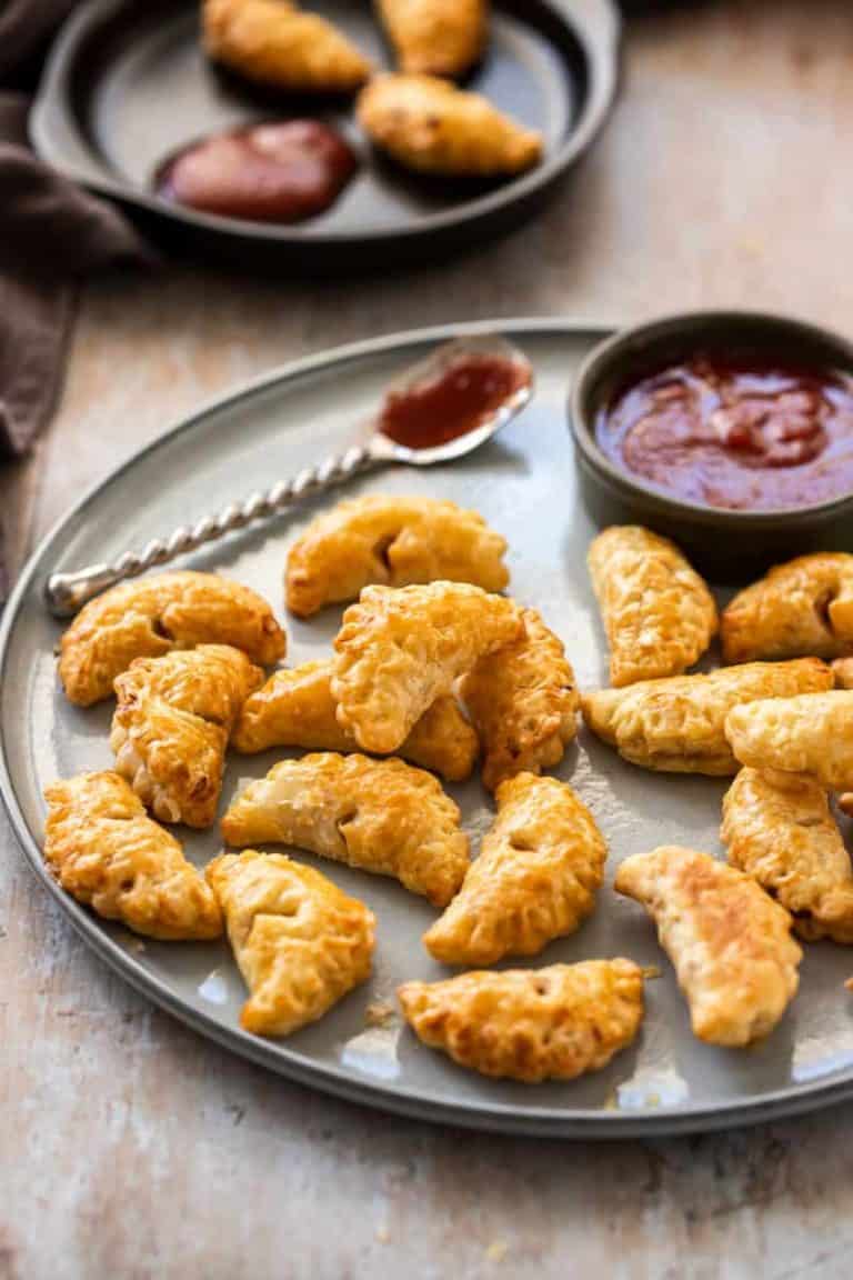 mini bacon onion pasties on a round platter with dipping sauce