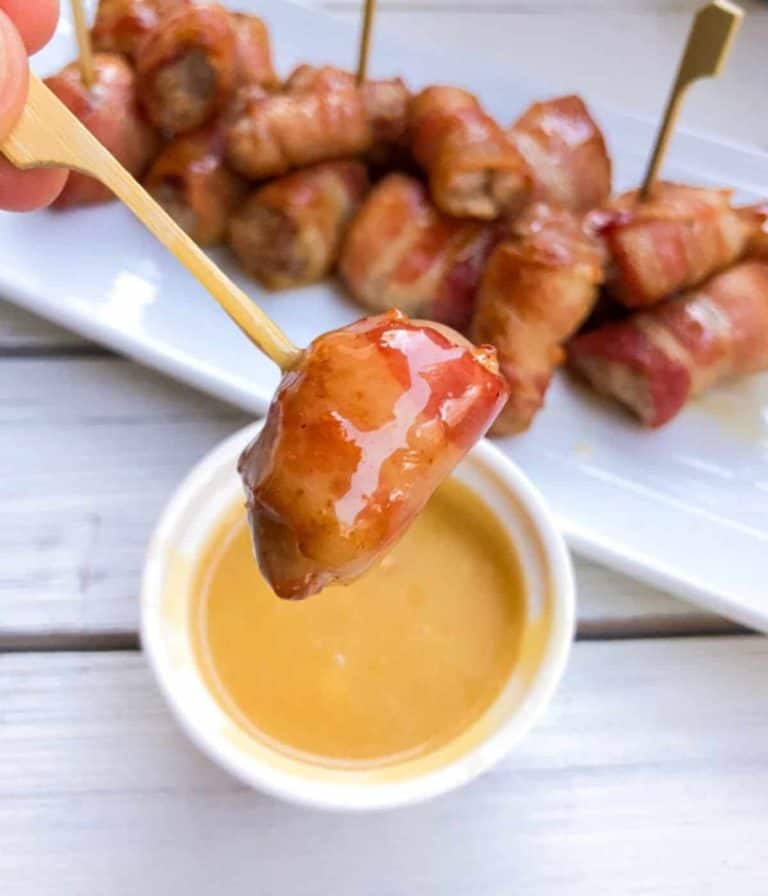 close up of maple wrapped pork bite on skewer with dipping sauce
