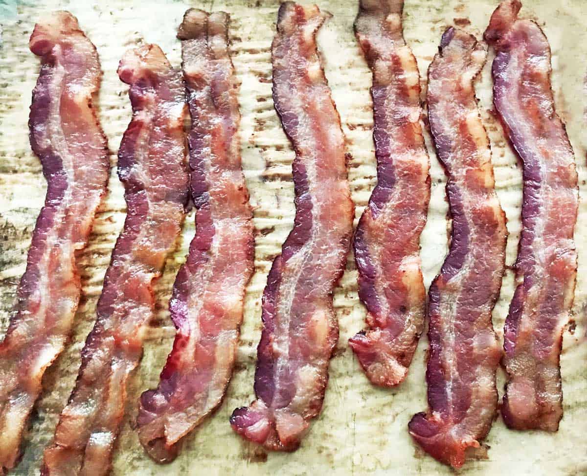 7 slices of oven cooked thick cut bacon on parchment paper.