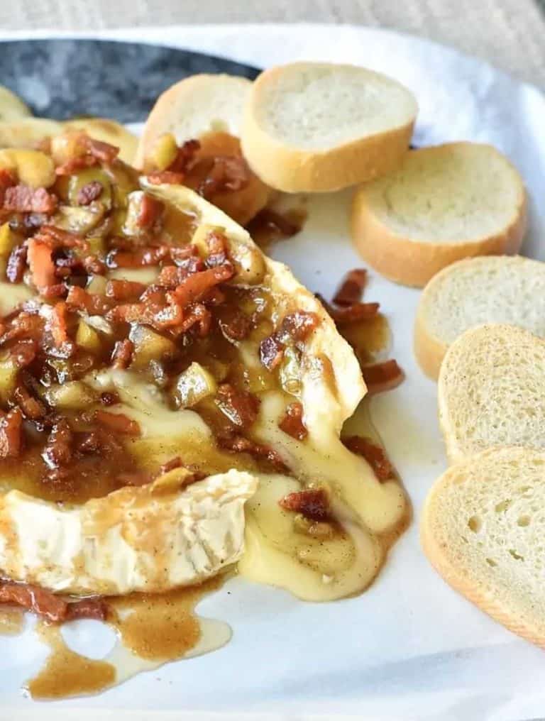 gooey baked brie topped with bacon and apple topping surrounded by 6 baguette slices