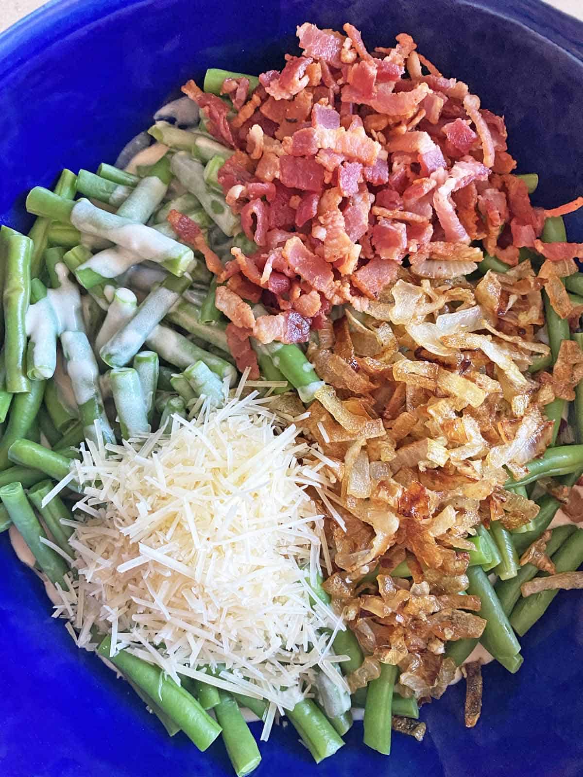 The cooked ingredients to make bacon green bean casserole in a blue bowl.