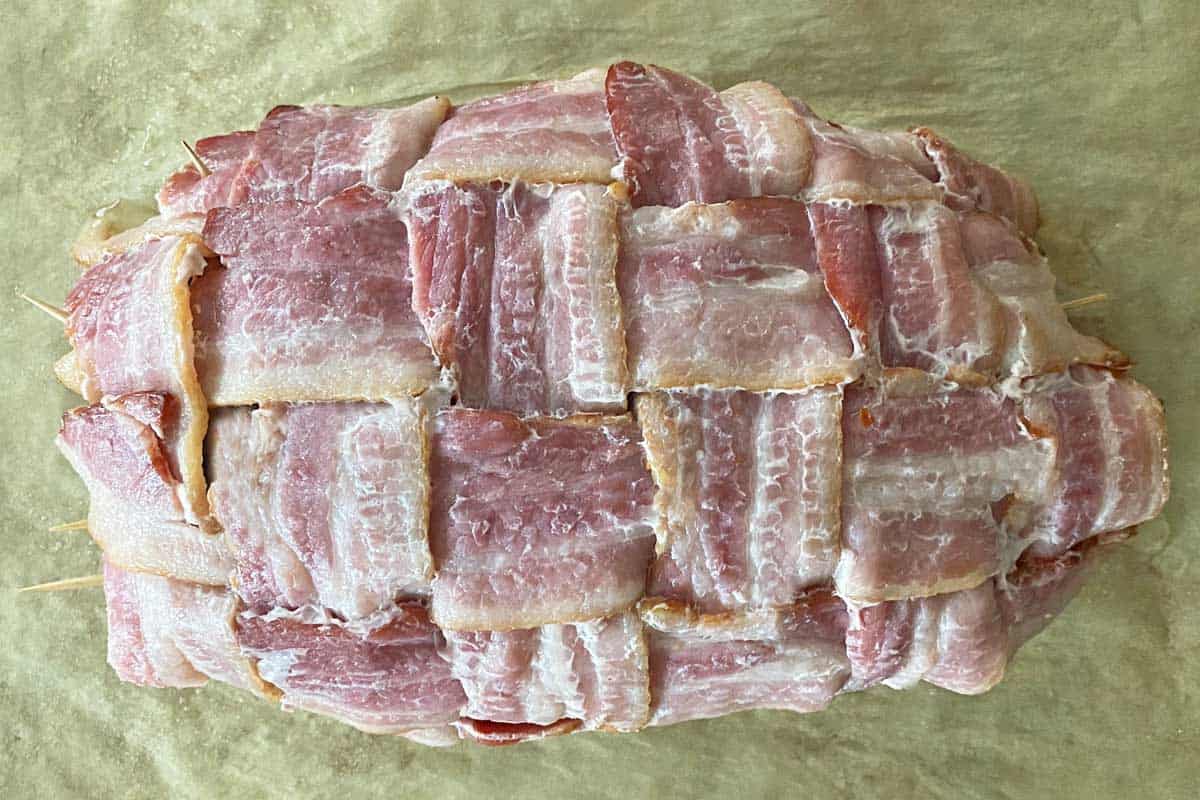 Meatloaf covered with a partially cooked bacon weave.