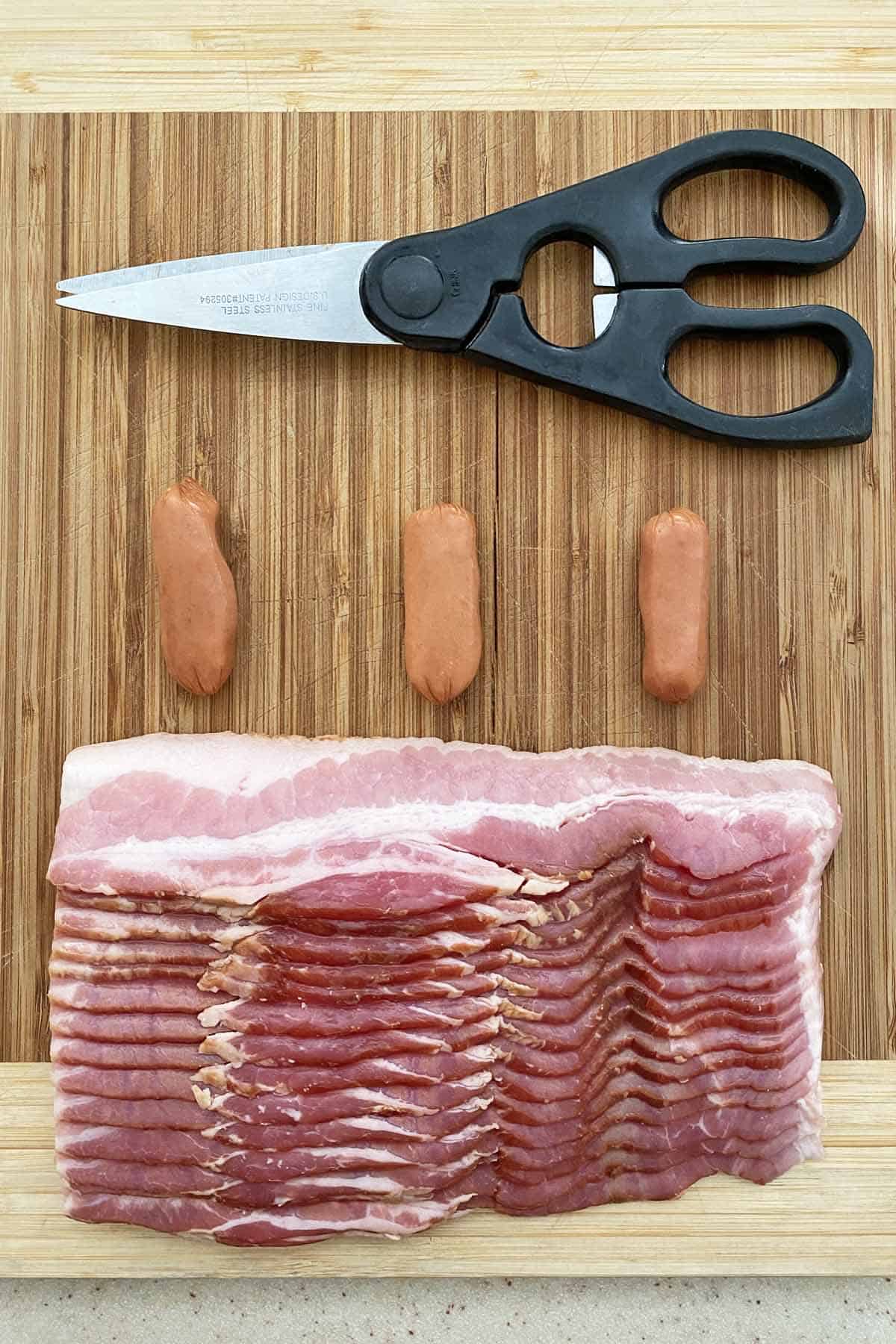 1 pound of center cut bacon, 3 llittle smokies sausages and a pair of kitchen scissors on a wood cutting board
