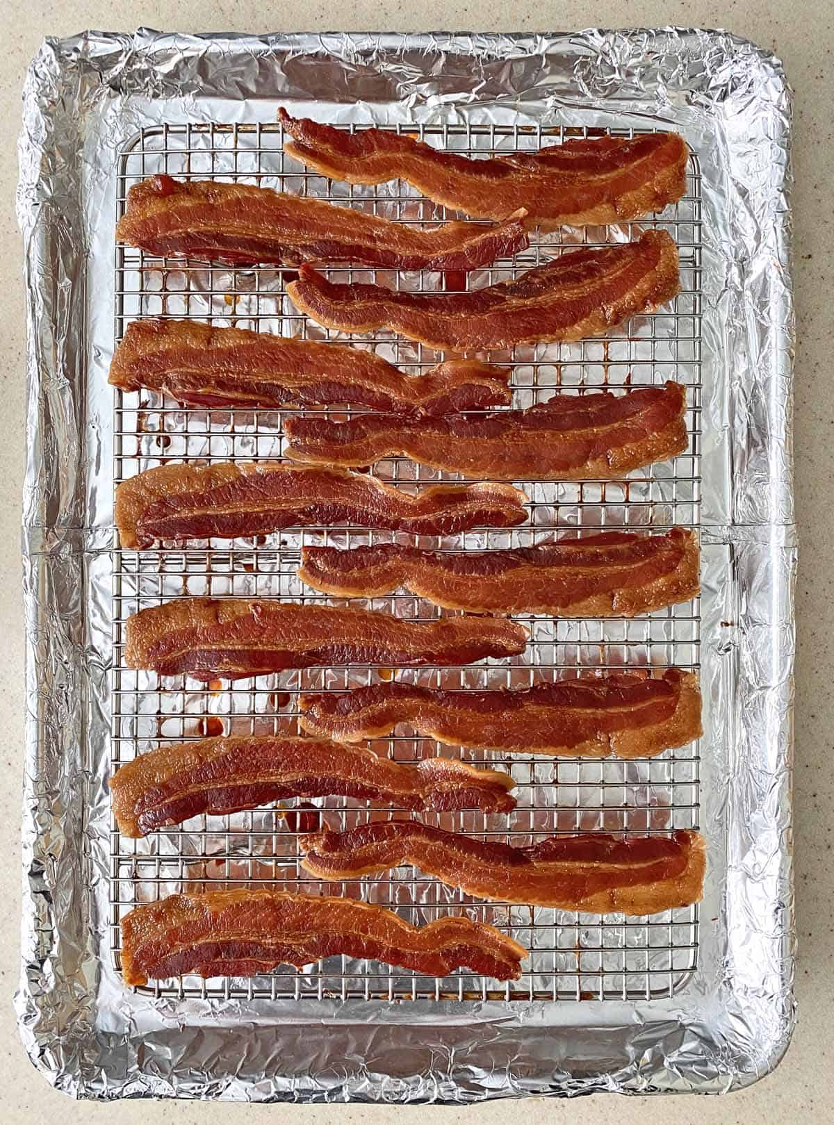 Fully cooked bacon jerky on a baking sheet, just after being pulled from the oven. 
