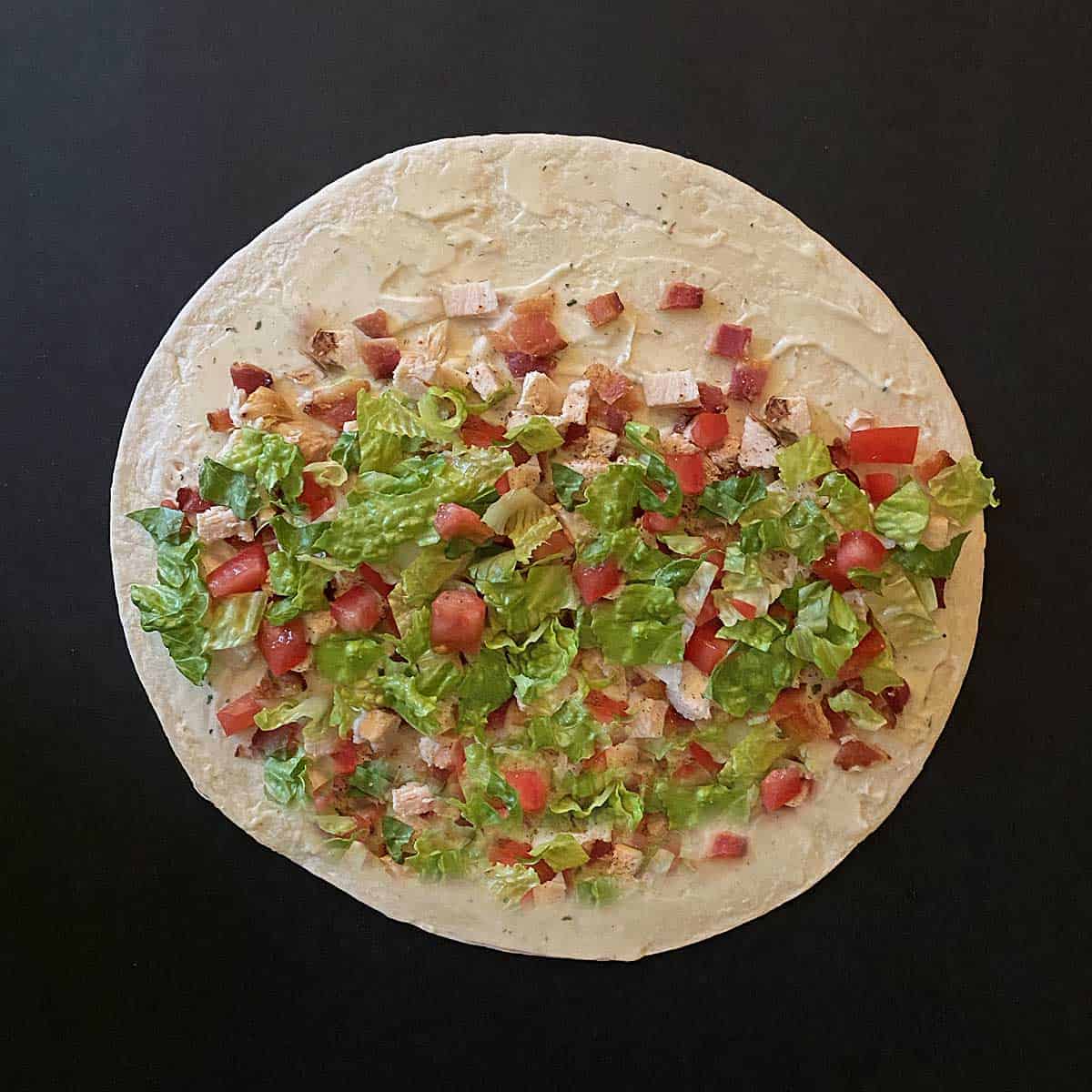 A flour tortilla spread with ranch mayo and sprinkled with chicken, bacon, lettuce and tomato.