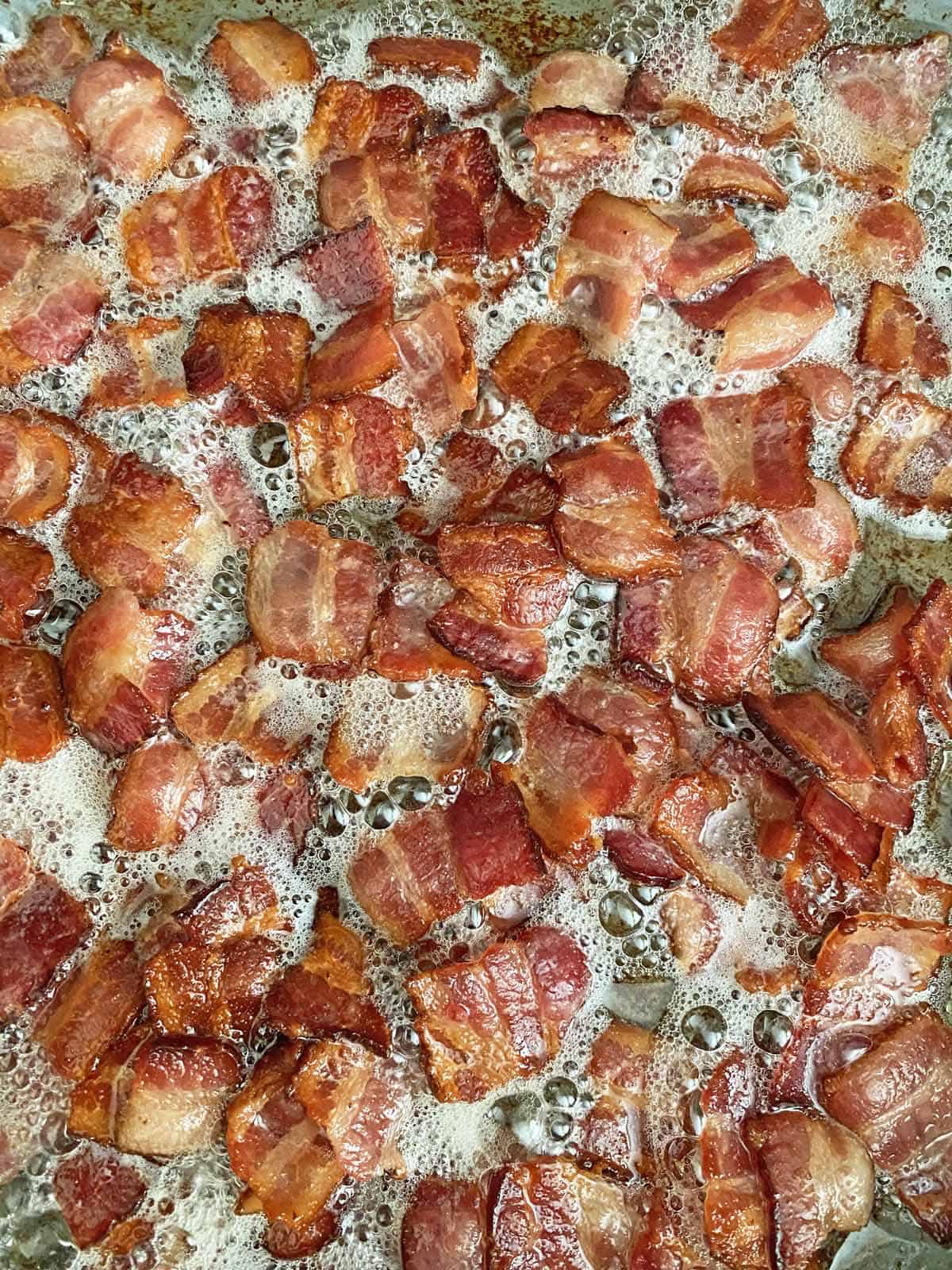 Close up of cooked chopped bacon in a hot skillet.