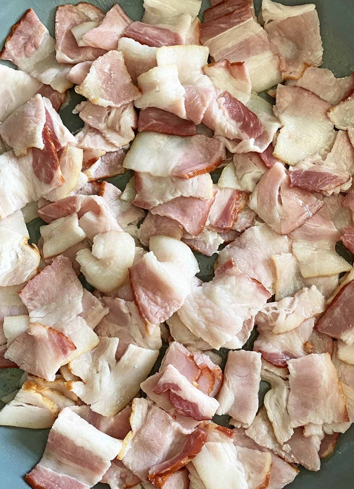Large pieces of chopped bacon in a gray skillet.