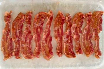 10 strips of brown, crispy microwave cooked bacon in a glass baking dish.