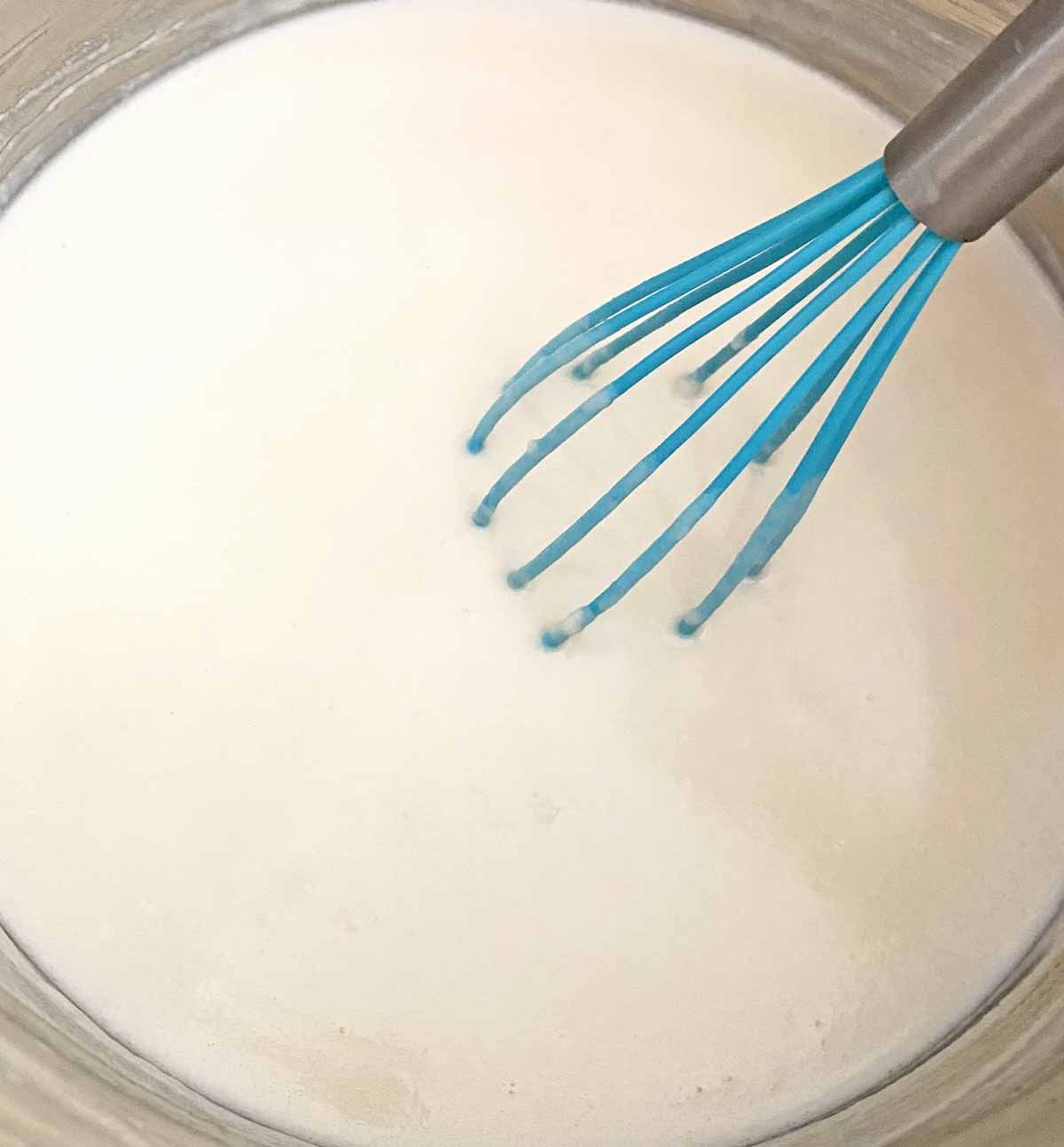 Whisking the cream soup mixture with a blue silicone whisk.