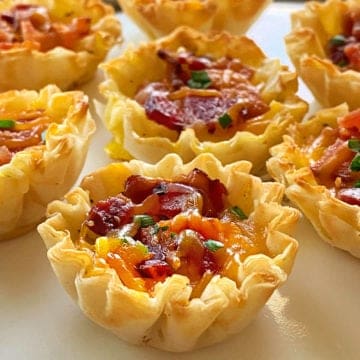 Close up of seven mini quiches with bacon, egg and cheese in phyllo cups.