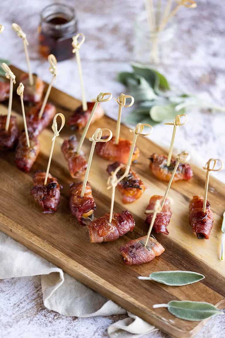 Bacon wrapped apricots on a wooden serving dish.