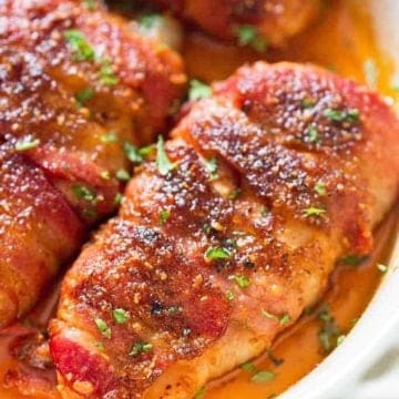 Three pieces of bacon-wrapped chicken breasts on a white plate.