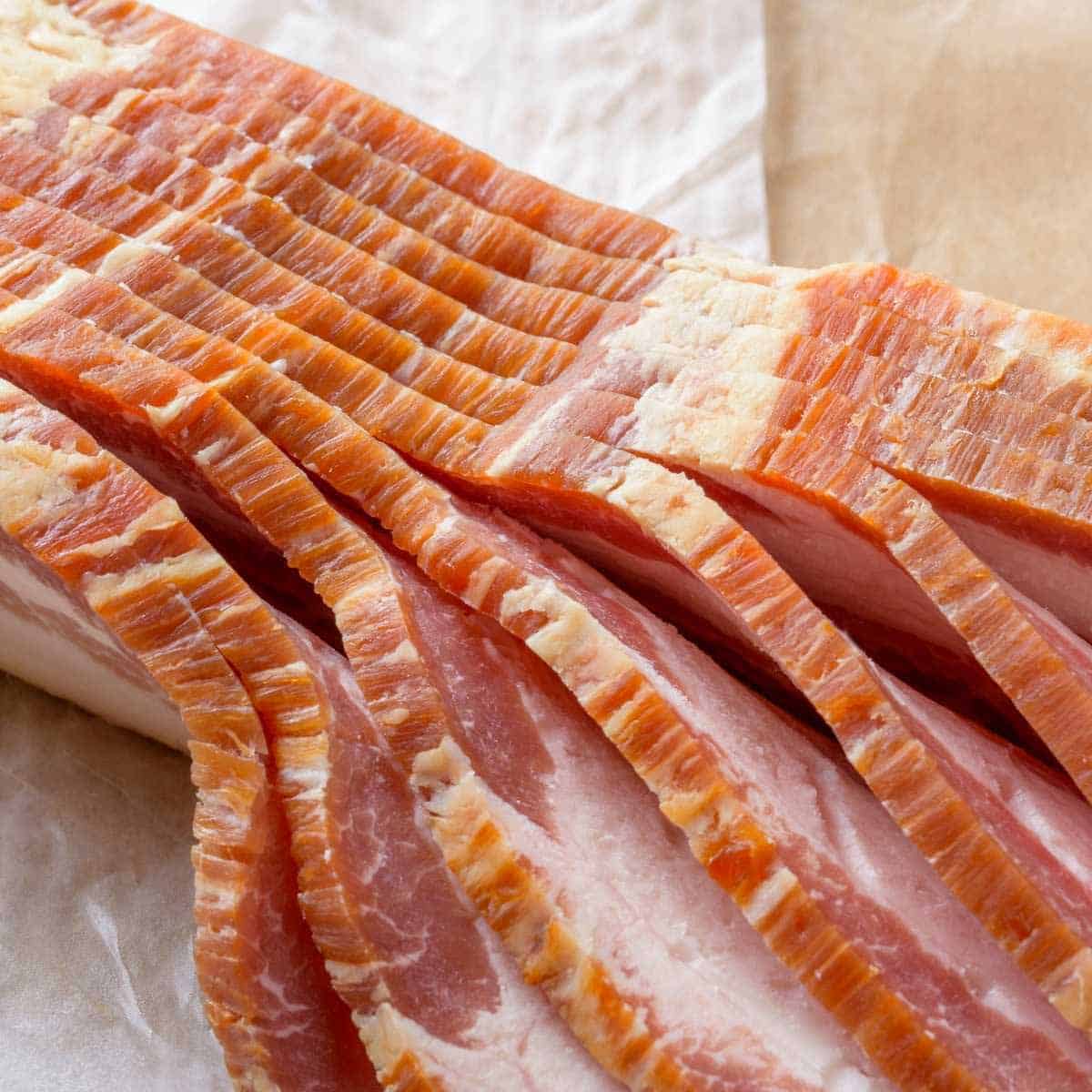 A pound of thick sliced bacon on a piece of butcher paper.