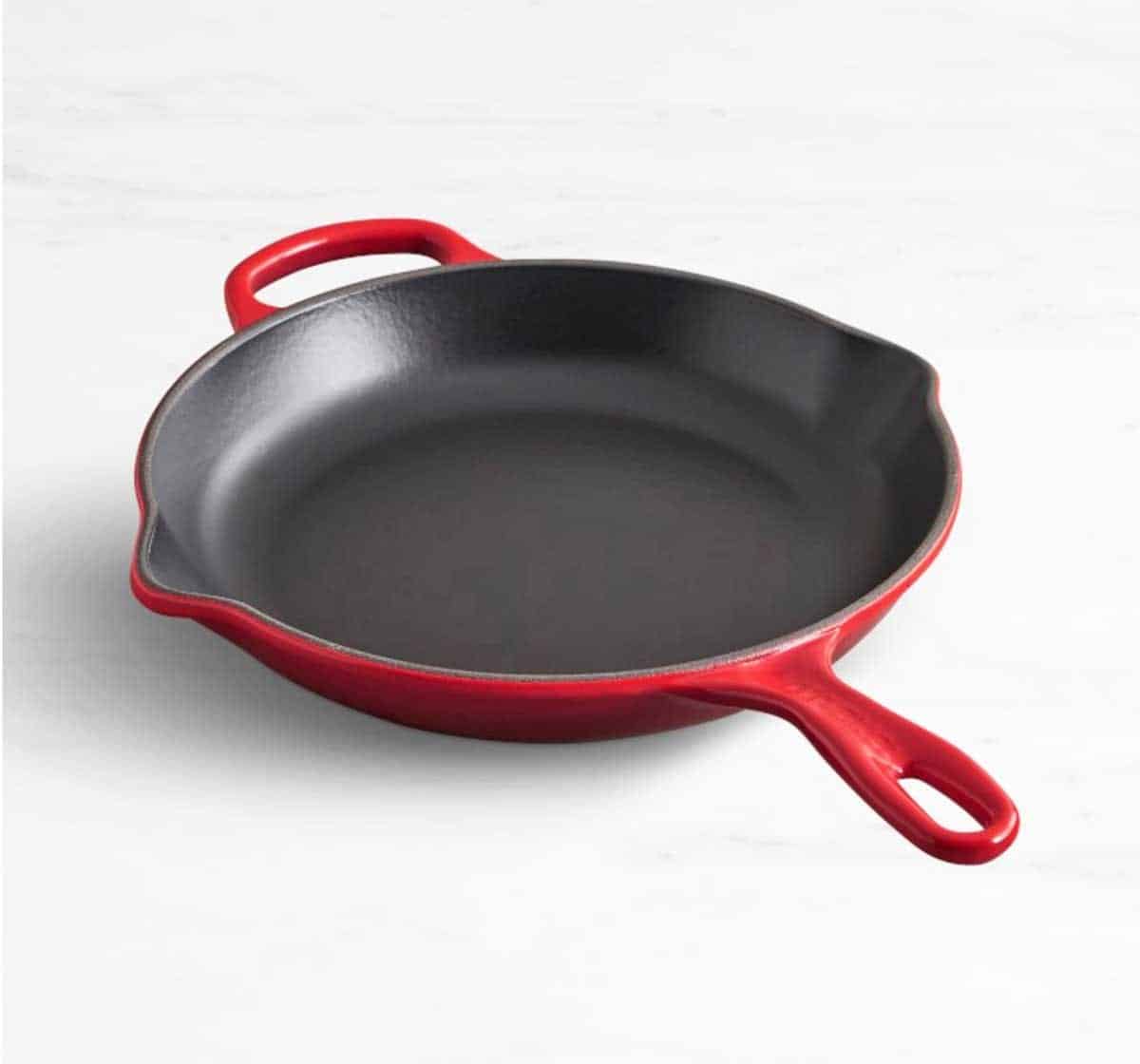 Le Creuset enameled cast iron skillet in cherry red color. 