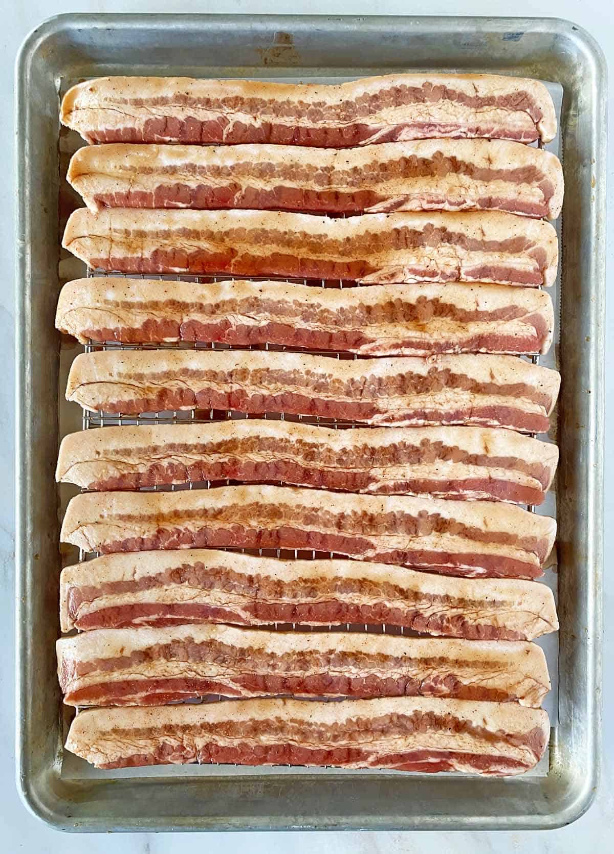 10 strips of uncooked million dollar bacon covered with glaze and ready to be baked in the oven.