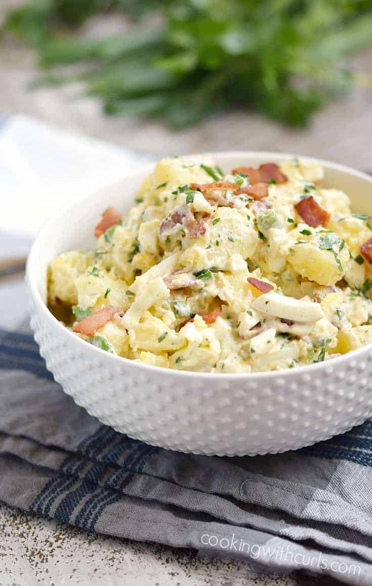 A white bowl filled with instant pot potato salad made with new potatoes, hard boiled eggs and bacon.