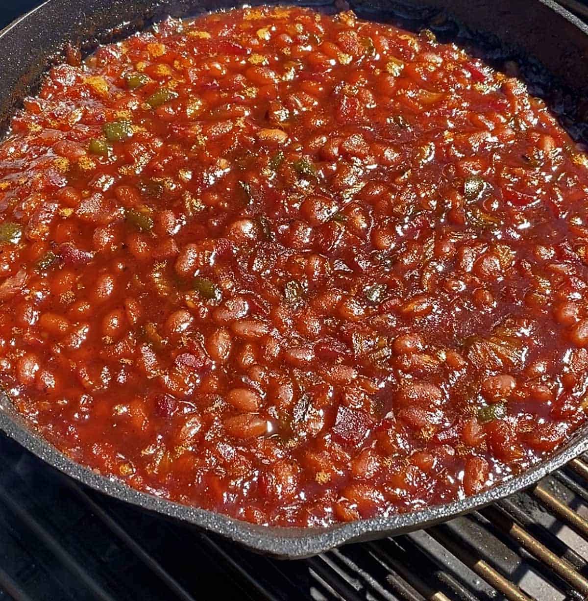 Cooked baked beans in a skillet ready to be removed from the smoker.