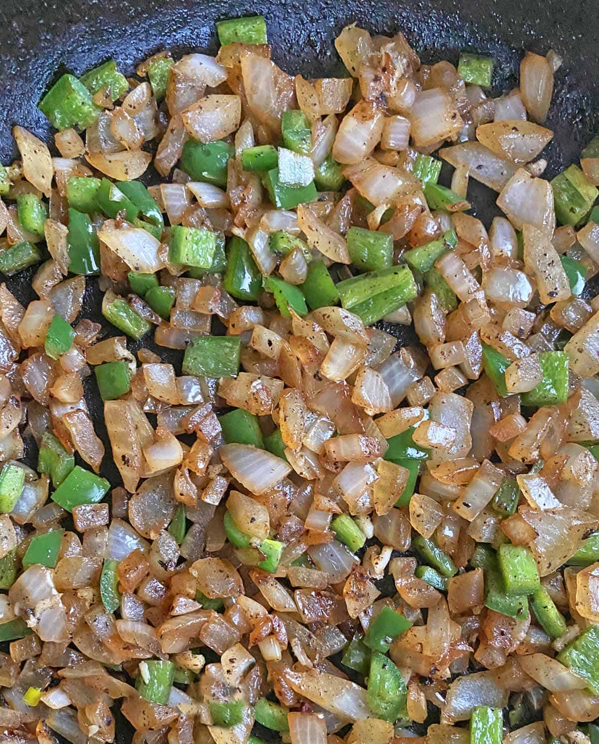 Chopped onions and jalapenos cooking in a skillet.