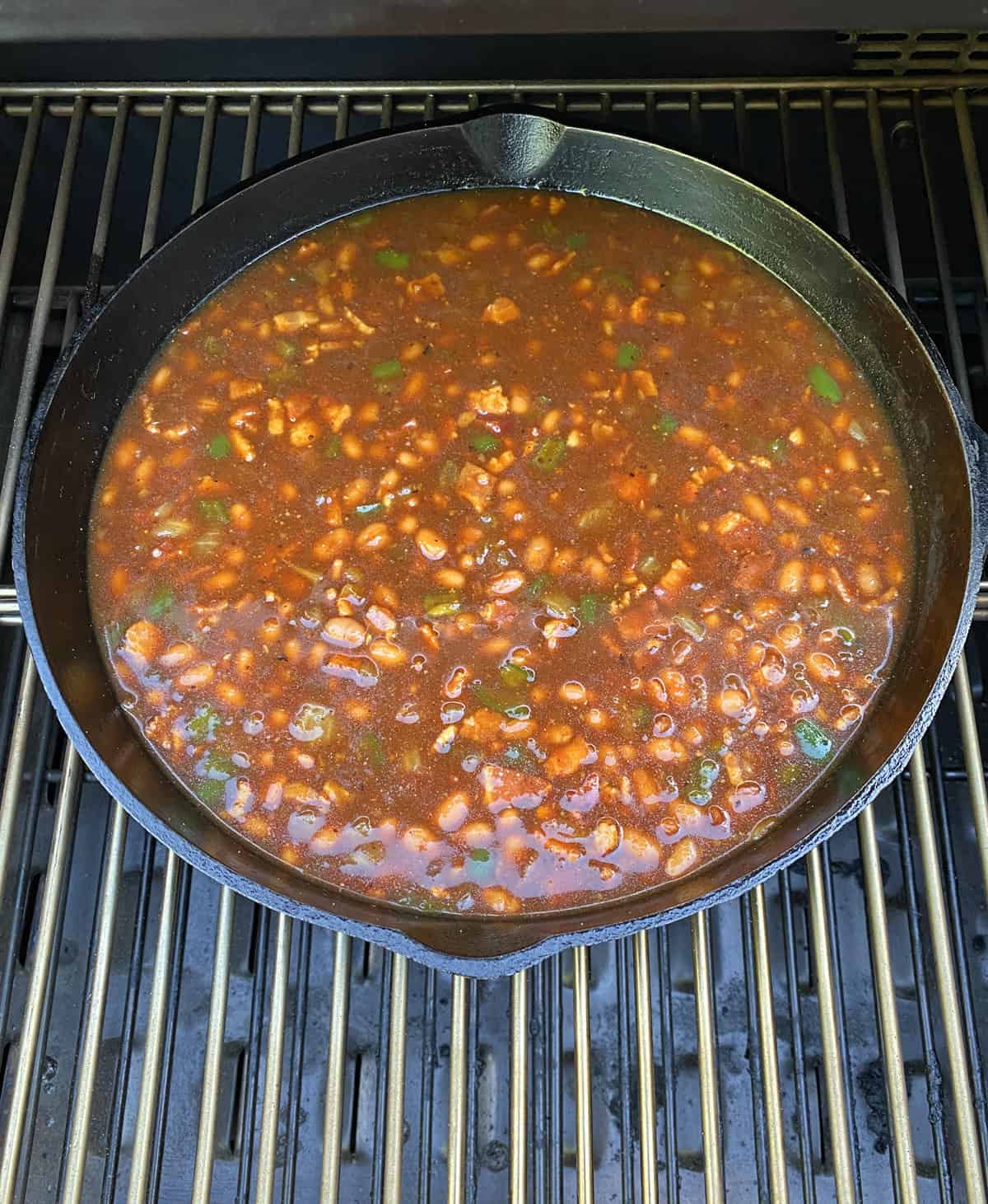 Placing the skillet of baked beans in the smoker.