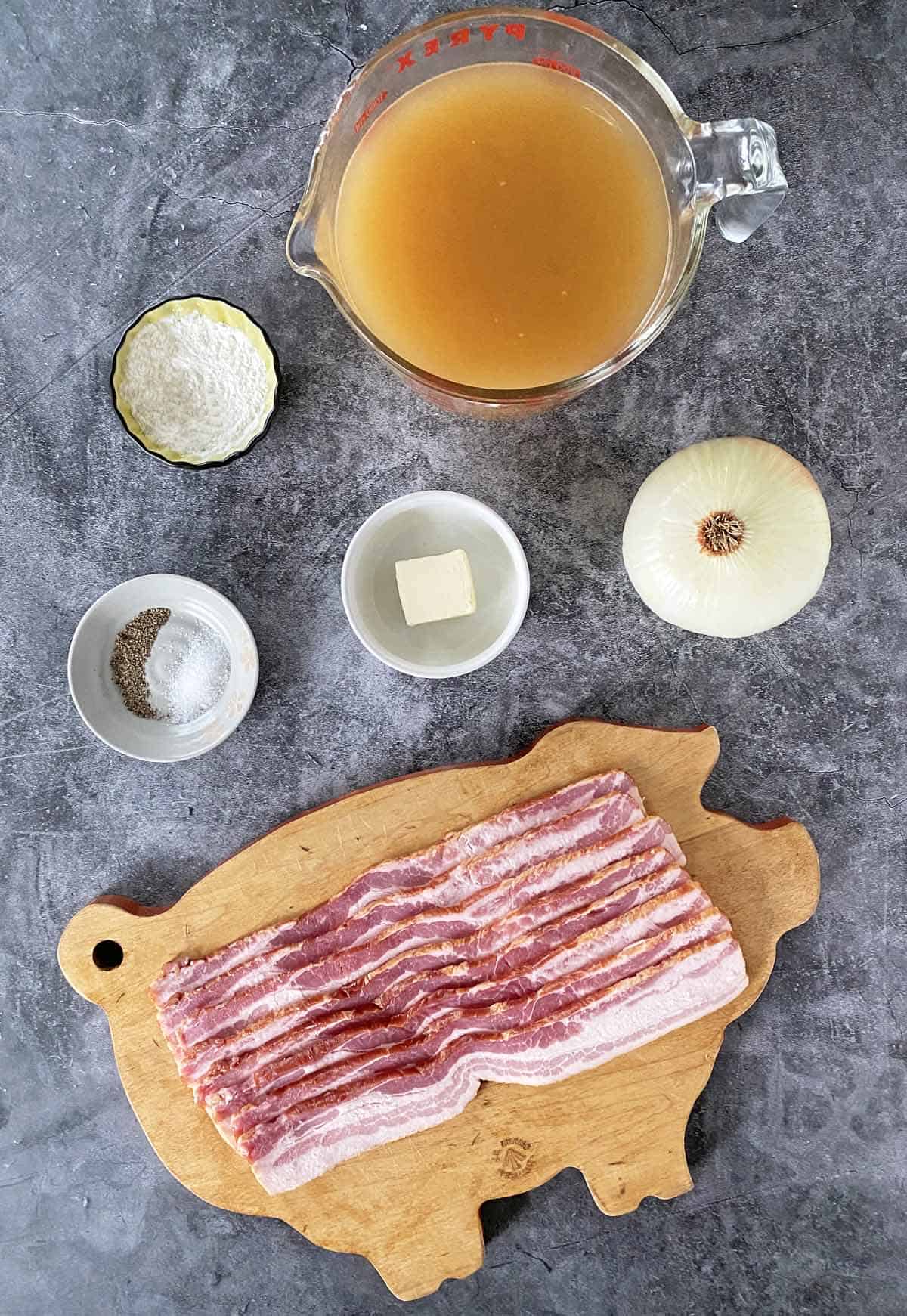 Broth, flour, butter, onion, salt and pepper and a pound of uncooked bacon on a cutting board.