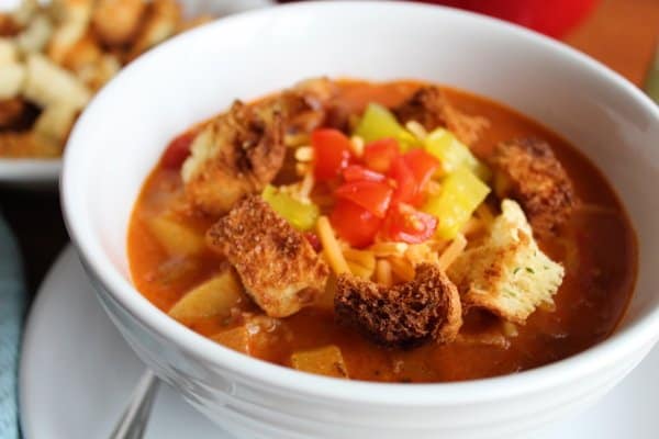 A white bowl of bacon cheeseburger soup topped with croutons.
