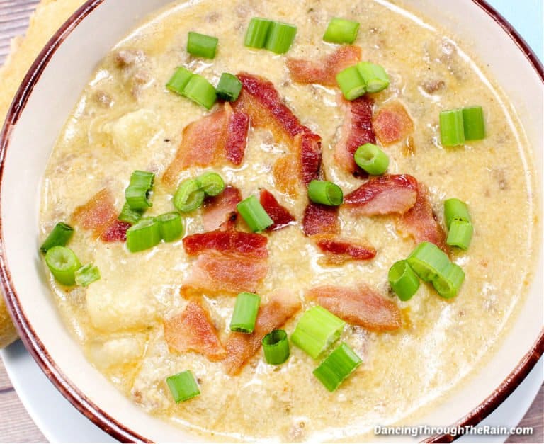 A white bowl of cheeseburger soup topped with bacon and green onions.