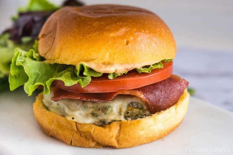 A turkey burger topped with bacon, tomato and lettuce.