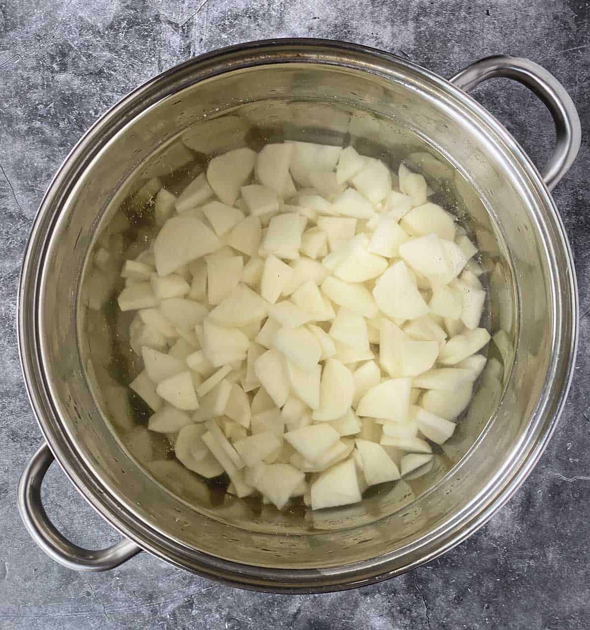 Cut potatoes in a large stainless steel pot of water.