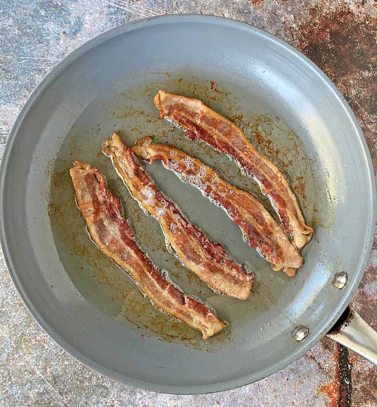 4 slices of bacon cooked until golden brown but still flexible in a large skillet.