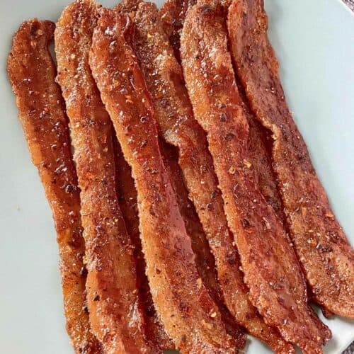 A pile of golden brown cooked Billionaire Bacon on a pale blue serving plate.