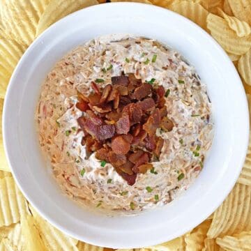 Finished bowl of cream cheese dip with bacon and caramelized onions, garnished with chopped chives.