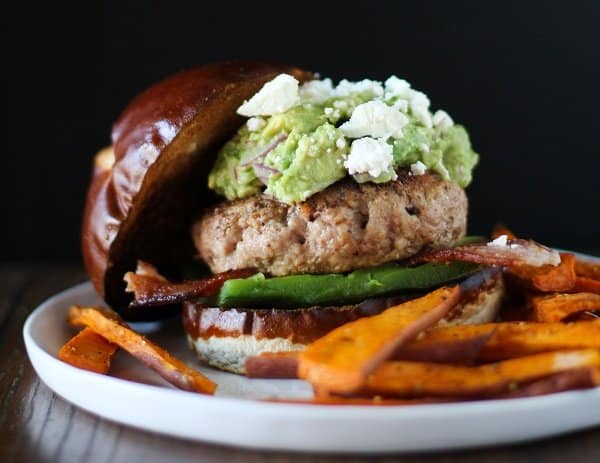 A bacon turkey burger topped with guacamole and served with fries.