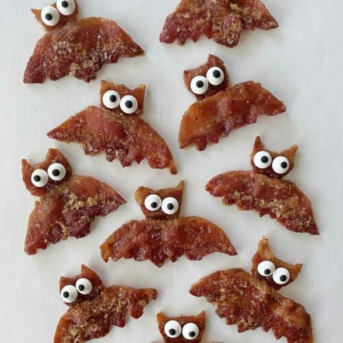 Ten finished maple bacon bats on white parchment paper.