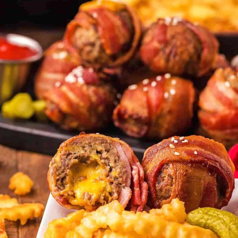 Eight bacon wrapped burger bites with french fries and ketchup.