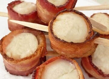 Seven cooked scallops wrapped in bacon and just out of the oven.