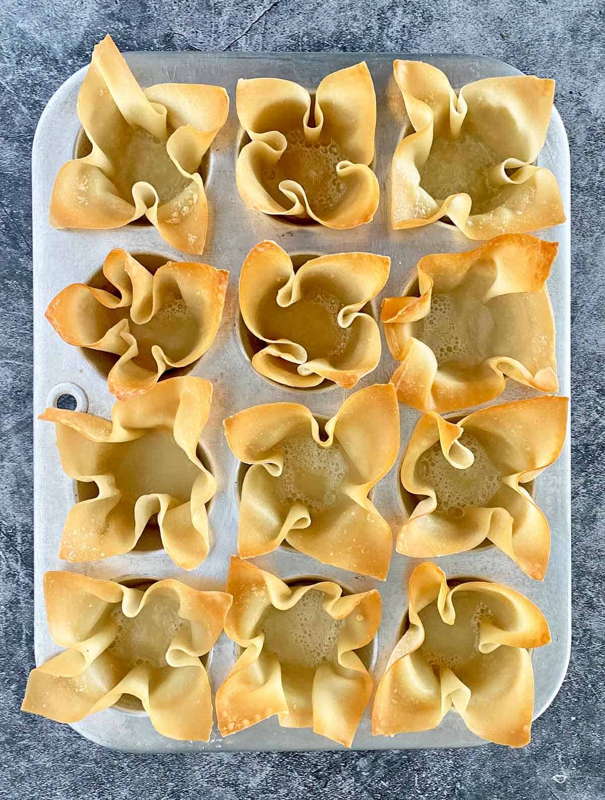 A dozen golden brown baked wonton cups ready to be filled with jalapeno popper bacon filling.