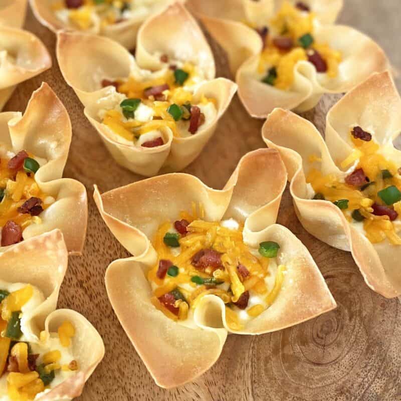 Baked wonton cup appetizers on a wooden board ready for serving.