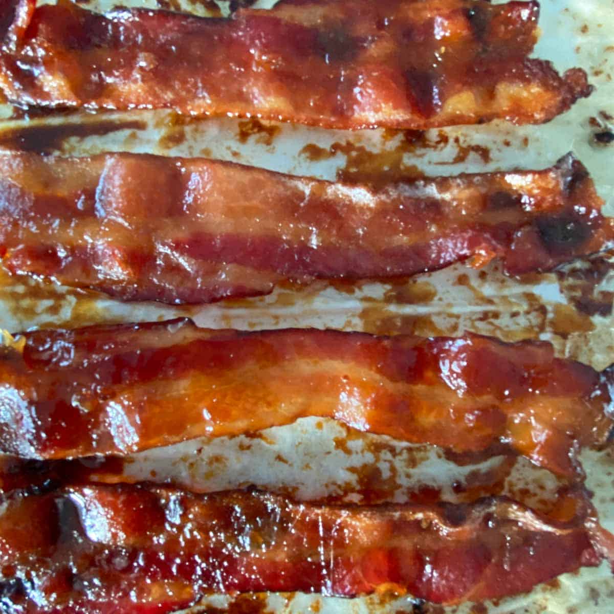 4 pieces of cooked maple candied bacon on a baking sheet.