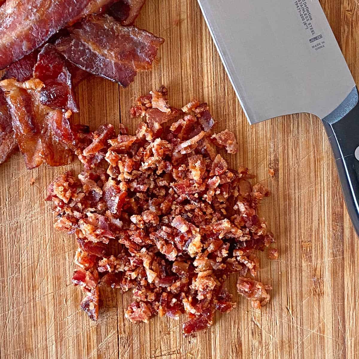 Chopped candied maple bacon and a knife on a cutting board.