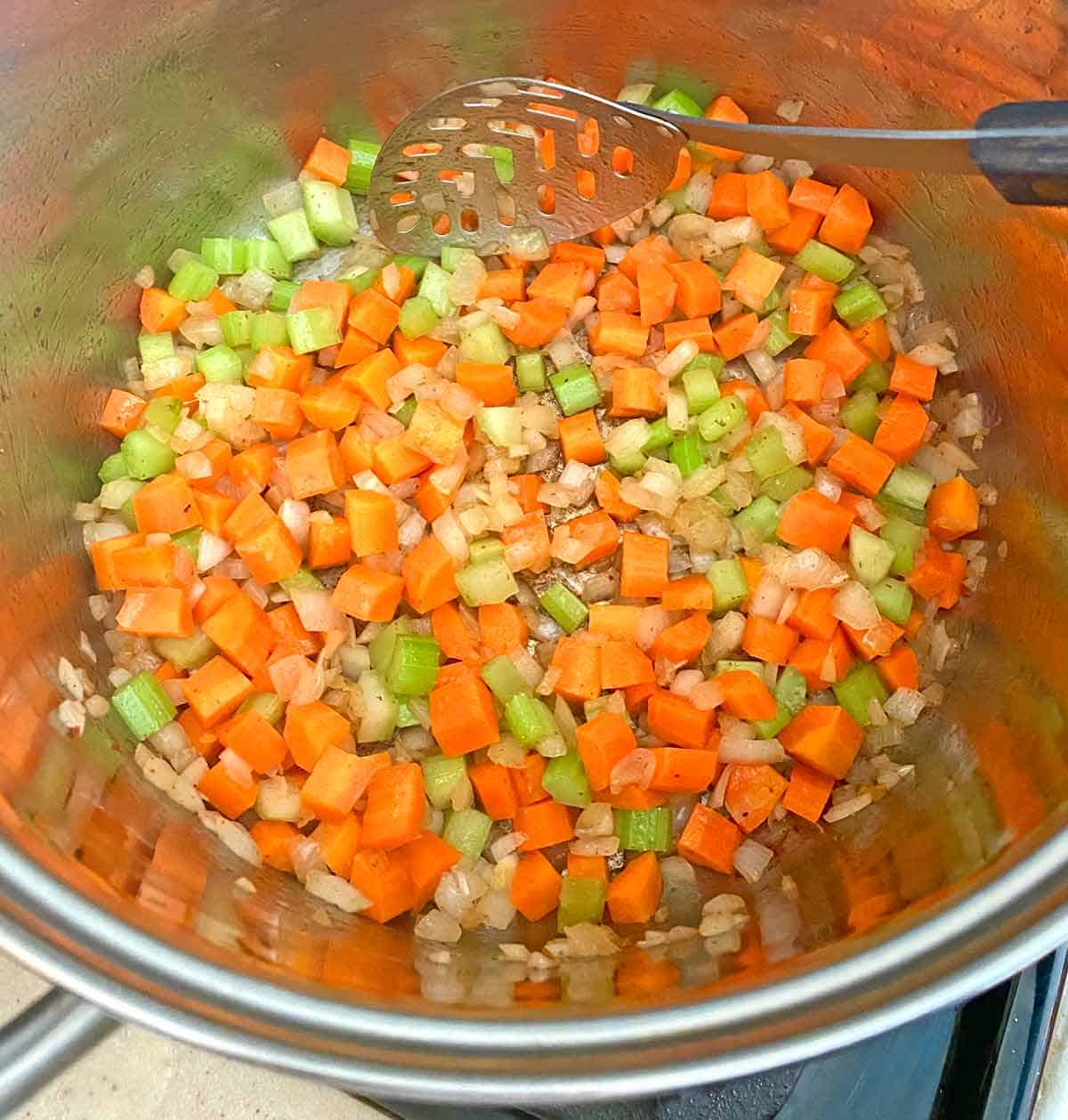 Cooking chopped celery, carrots and onion in a large soup pot.