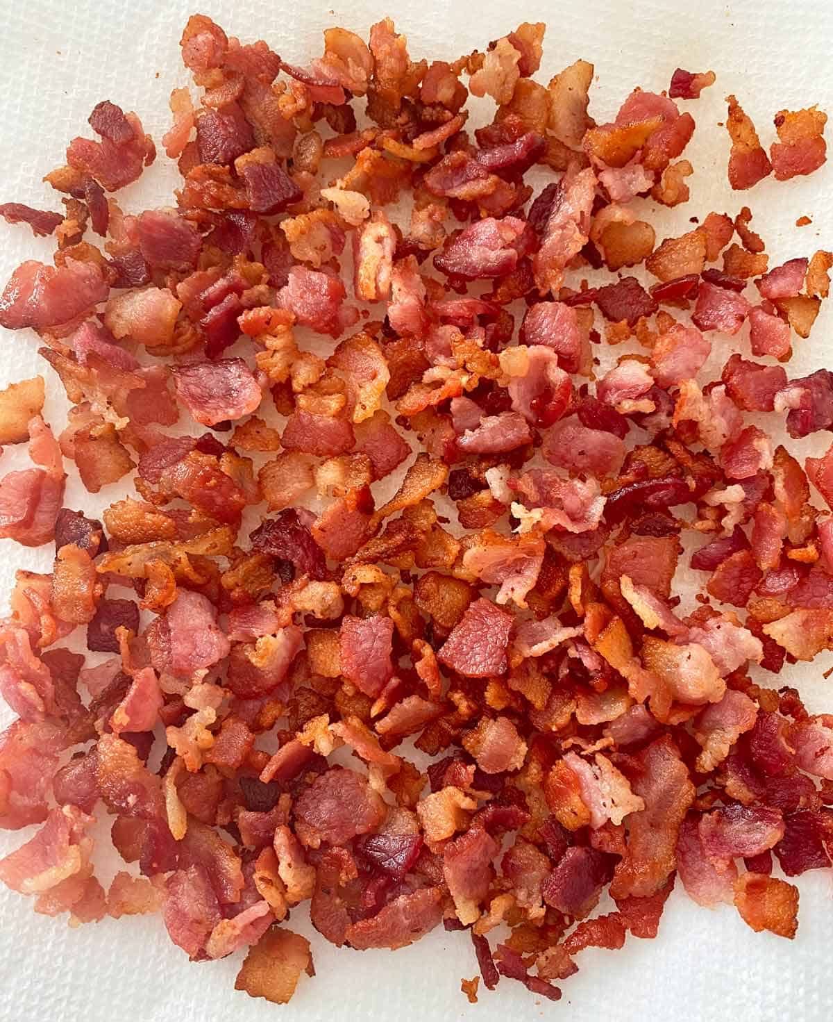 Golden brown cooked chopped bacon draining on paper towels.